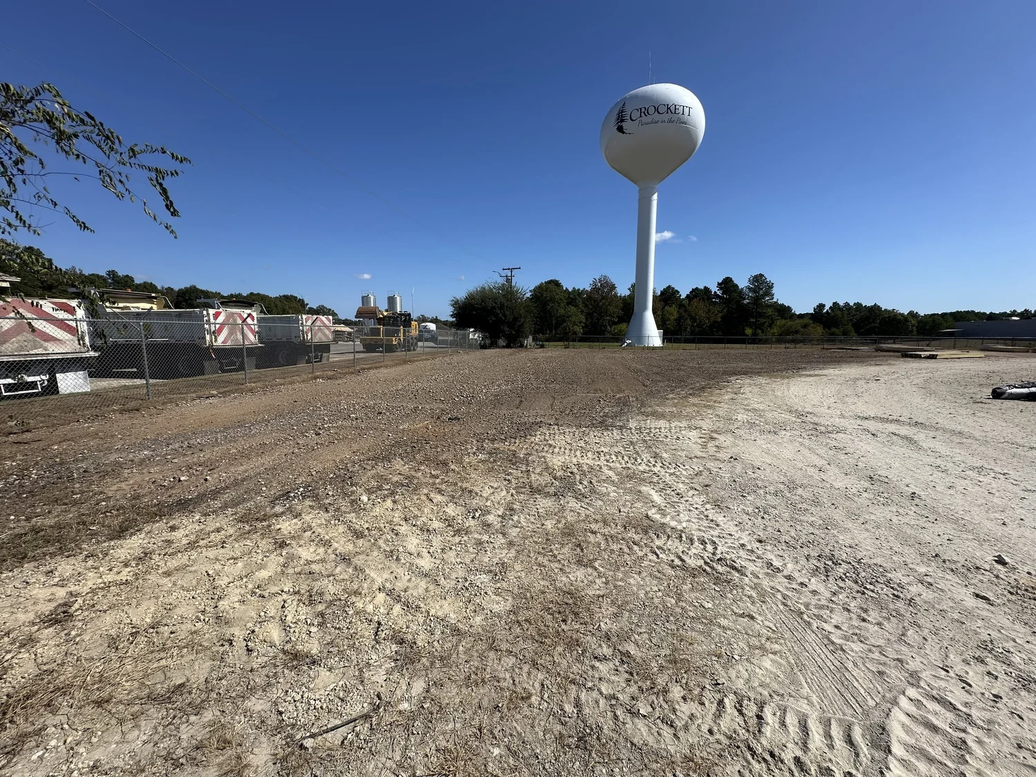 Open dirt site with prepared ground beside a fenced area